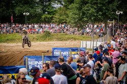 Das Bild zeigt einen Motocrossfahrer im leichten Sprung umringt von zahlreichen Zuschauern